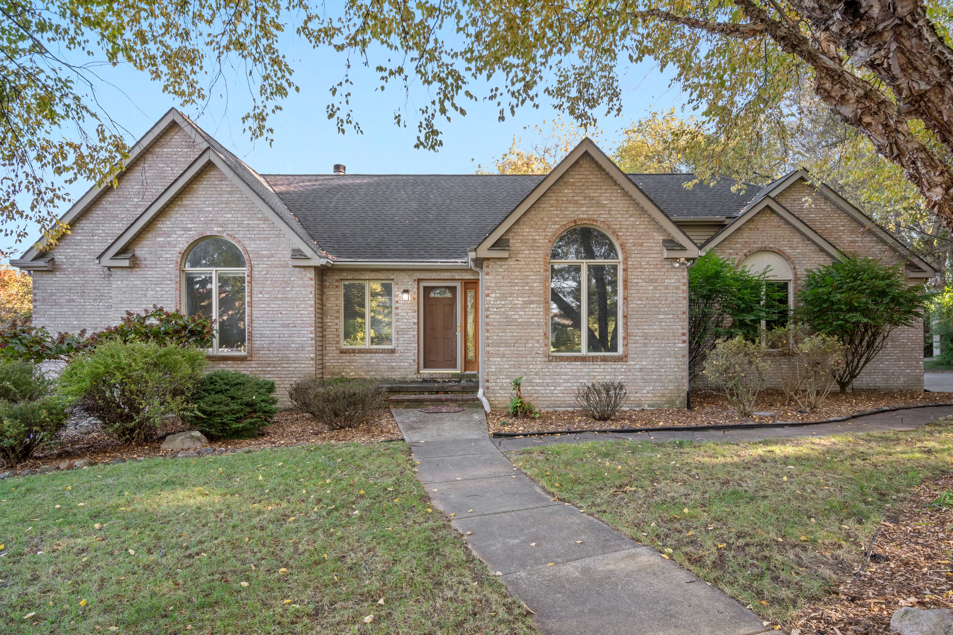Brick home midday exterior — flat sky, harsh shadows on lawn